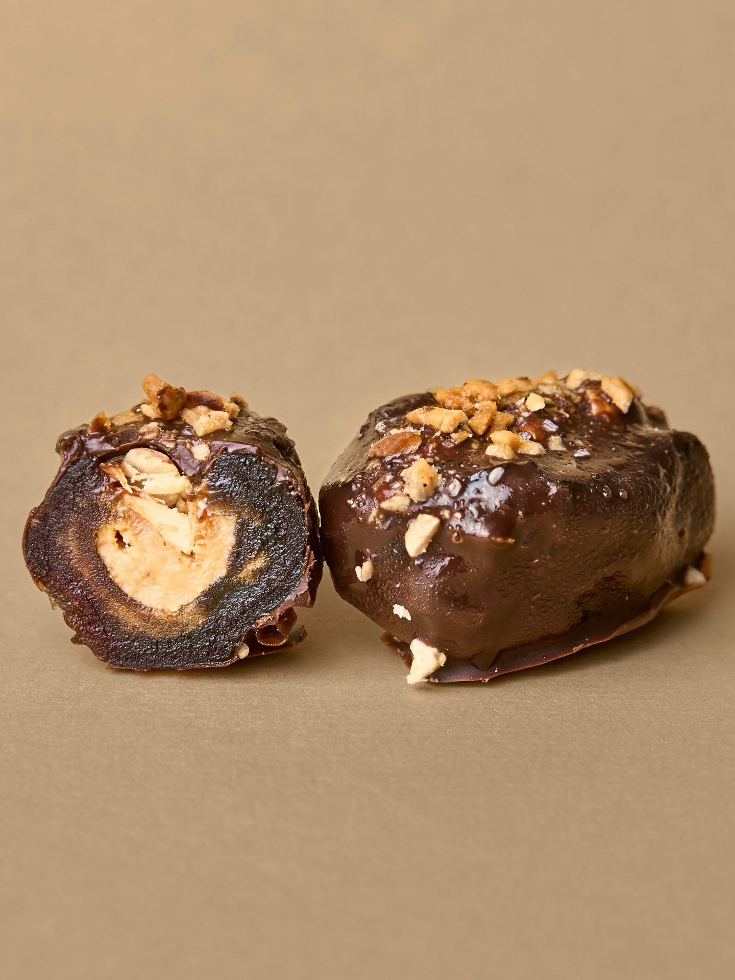 A PITT Peanut date split open beside a whole one, the peanut butter filling visible
